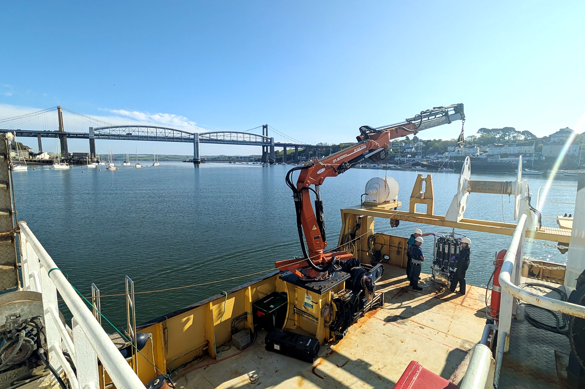 Scientists on board the Quest research vessel next to a rosette with the Tamar Bridge in the background